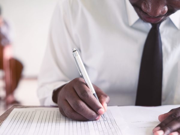Exam with african man doing educational test with stress in classroom.